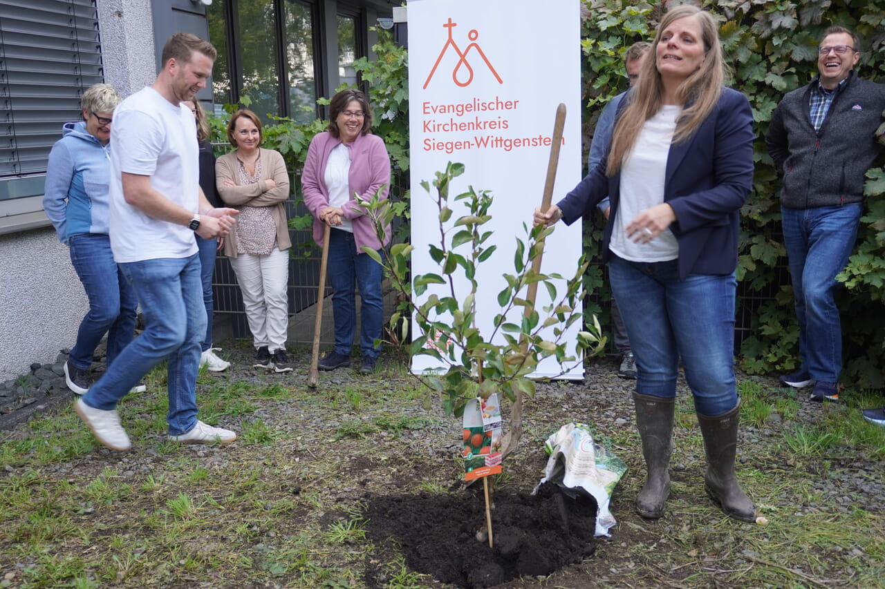 Die Superintendentin Kerstin Grünert nahm die Challenge an und pflanzte ein Apfelbäumchen im Außenbereich des Kreiskirchenamtes an der Weidenauer Straße.
