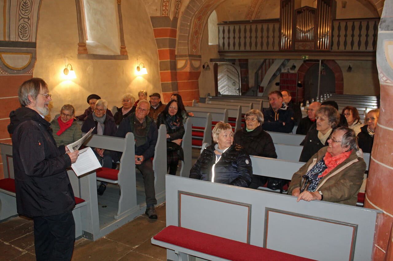 In der Puderbacher Kirche präsentierte der ehemalige Gemeindepfarrer Dieter Kuhli (links) den Zuhörinnen und Zuhörern verschiedene Argumente, die dafür oder dagegen sprachen, dass das Gebäude eine Wehrkirche ist.