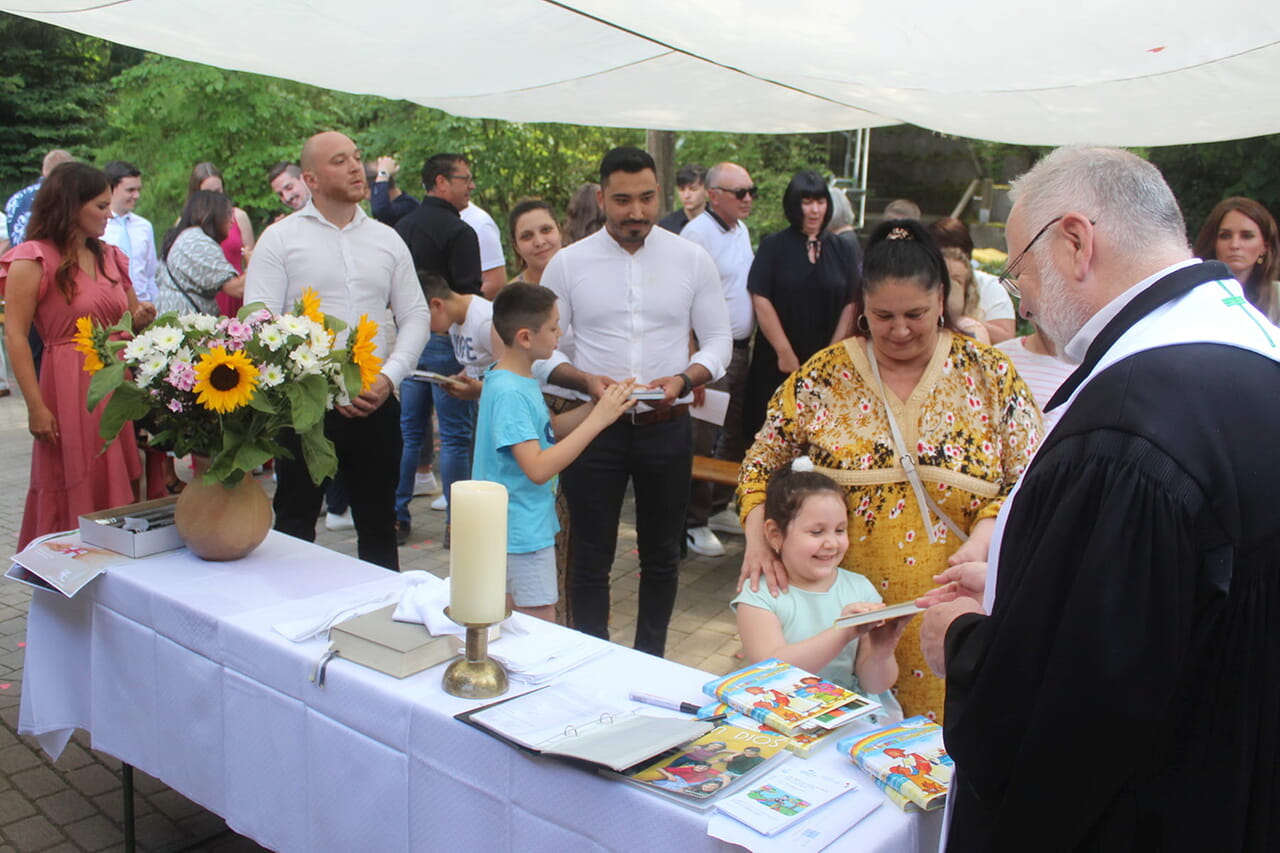 Nach dem Freiluft-Gottesdienst bei der Siegener Erlöserkirche gab es aus den Händen von Pfarrer Armin Pulfrich für die Täuflinge Kinderbibeln.