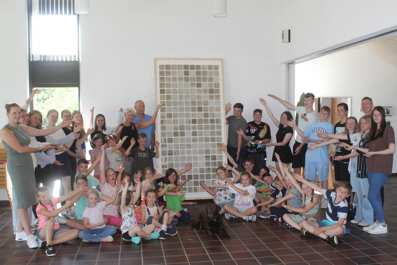Voller Freude präsentierten die kleinen und großen Kinder-Kunst-Woche-Teilnehmenden gemeinsam mit Pfarrer Martin Eckey das 210-Beton-Quadrate-Mosaik mit der frohen biblischen Botschaft der Mahnung und des Zuspruchs.